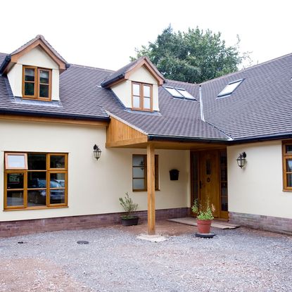 bungalow with grey roof and white wall with plant on pot