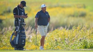 Photo of Bryson Dechambeau stood next to his golf bag