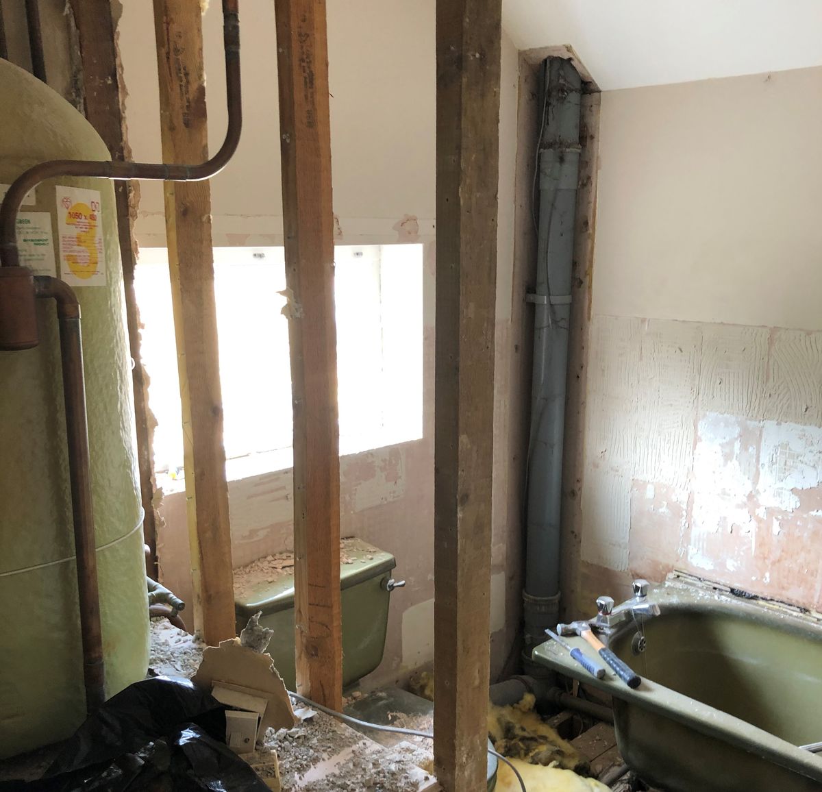 Avocado bathroom suite being ripped out with copper tank in the image