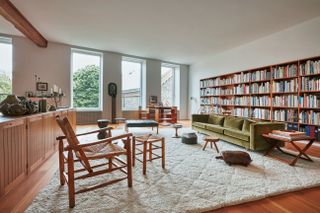 Living room interior with large bookcase, white area rug and green sofa