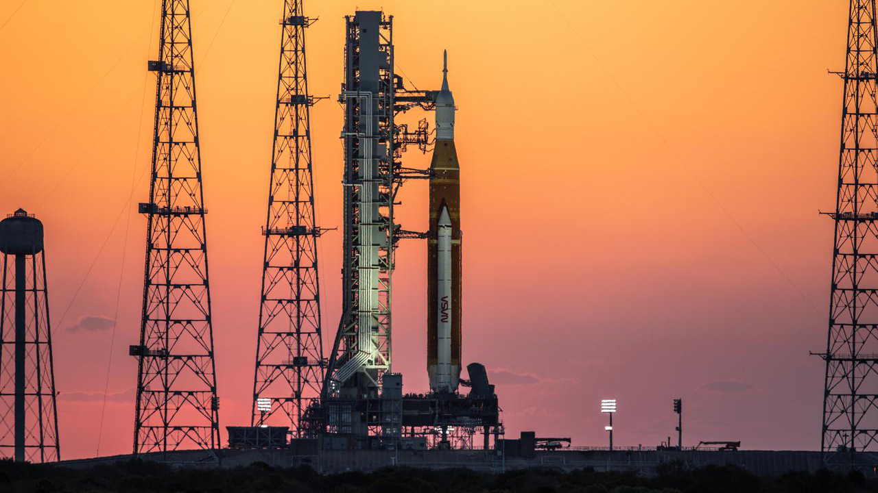 Восход солнца освещает теплым светом космический корабль «Орион» и космическую систему запуска «Артемида I» (SLS) на стартовой площадке 39B в Космическом центре НАСА Кеннеди во Флориде 21 марта.