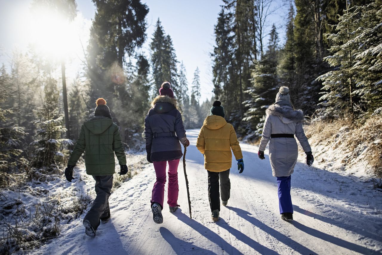 Four women walk down a snow covered road