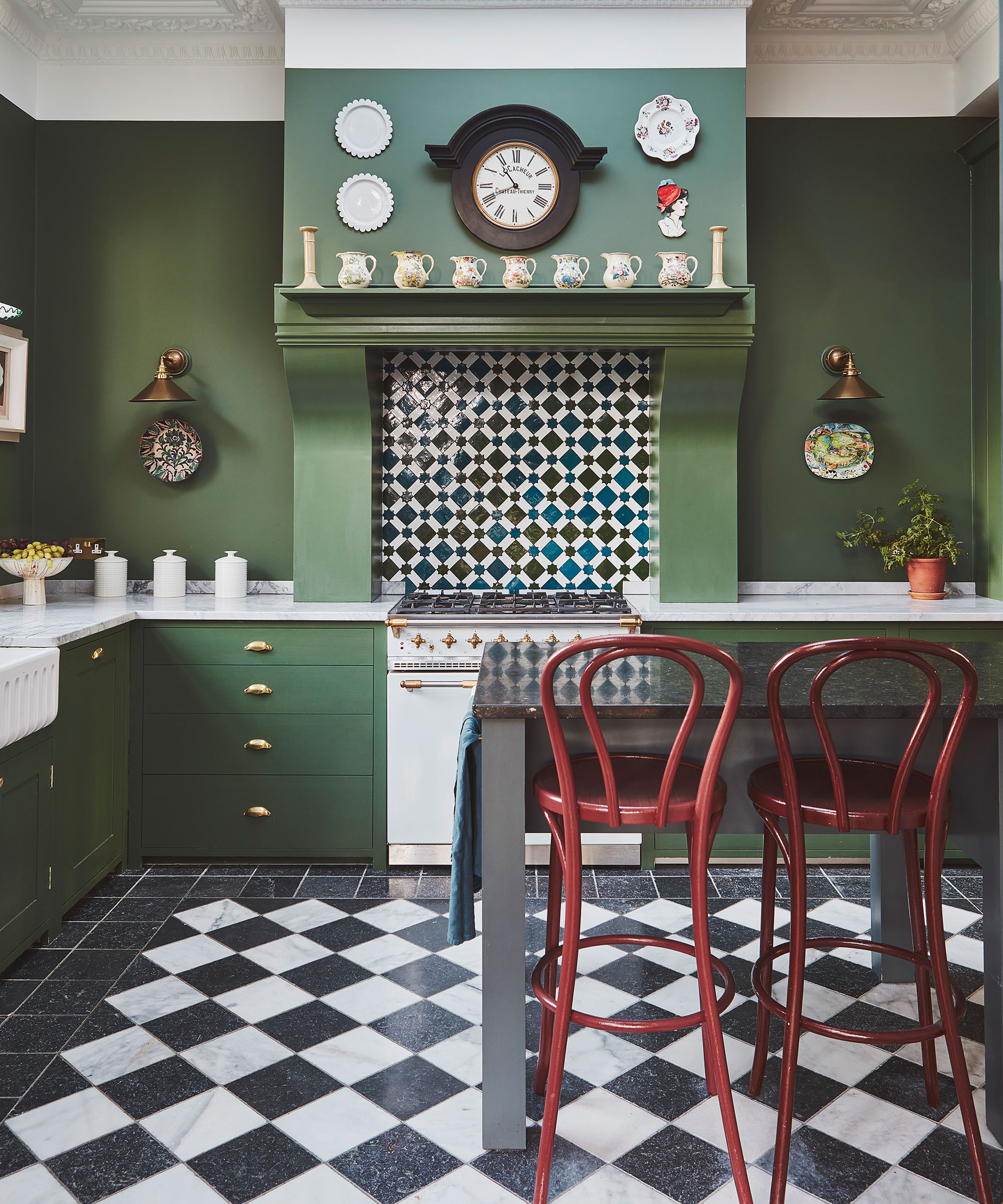 green farmhouse kitchen with black and white chequerboard flooring and red bar stools
