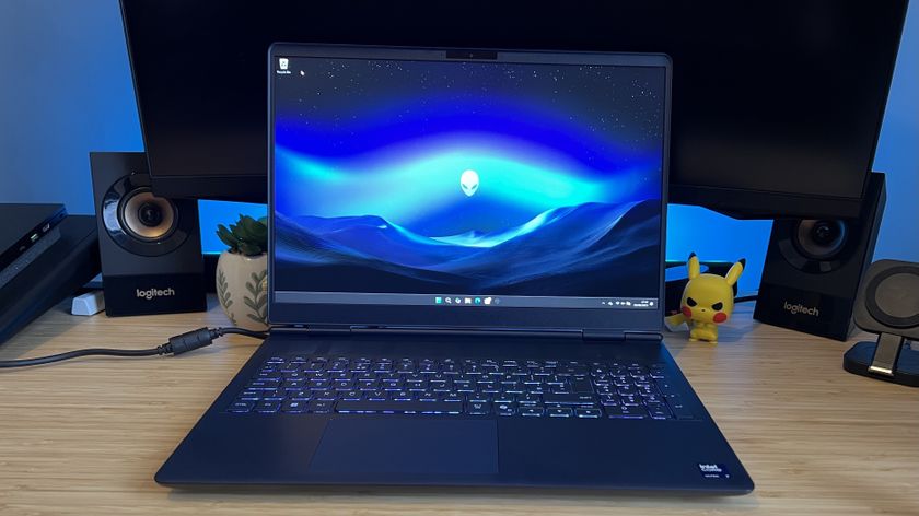 Alienware 16X Aurora gaming laptop open on a wooden desk with blue backlighting