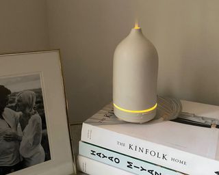 iHeoco Stone Diffuser on Melissa's nightstand ontop of a stack of books with a photo frame beside it