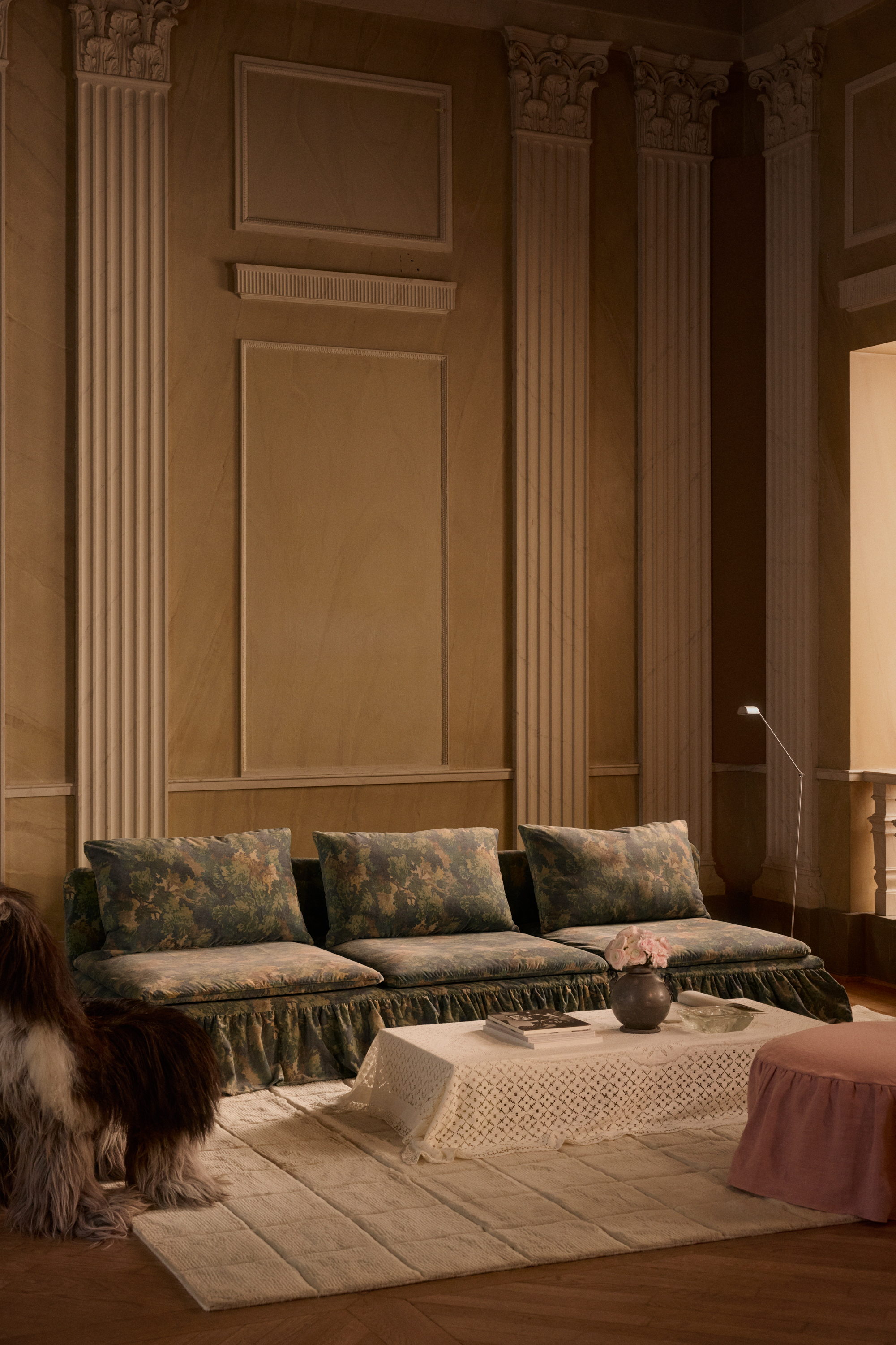 Bemz x Francesca Grace collaboration on sofa in traditional living room with coffee table draped in fabric and fluffy armchair and wall paneling behind the sofa