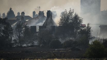 The smouldering ruins of houses following a large blaze in Wennington, Greater London