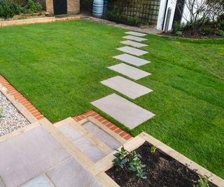 New turf installation around a new stepping stone pathway to a pebbled area and patio with steps