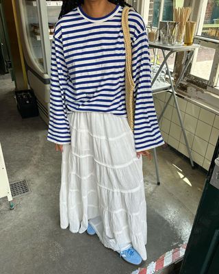 @amaka.hamelijnck wearing striped t-shirt, white ruffled skirt, and blue sneakers