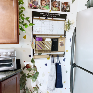 A kitchen command center with a calendar, letter holder, and photos