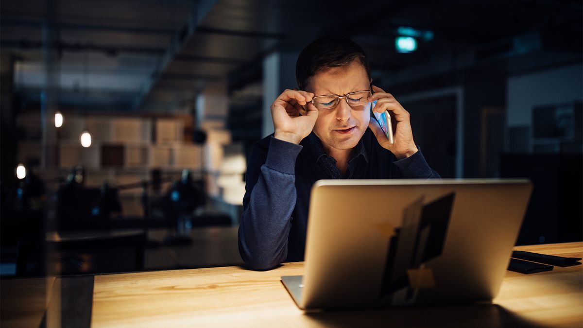 Businessman taking a call from a ransomware group in a dark office space at night.