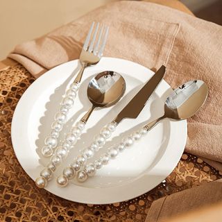Pearl stainless steel cutlery set on white plate