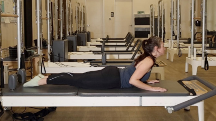 Woman on a Reformer Pilates machine demonstrating an exercise