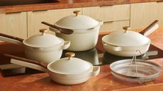 Our Place Vanilla Bean cookware collection on red travertine counter with timber joinery