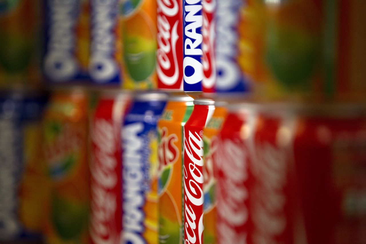 Soda cans sit on a store shelf