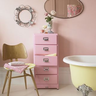 pink bathroom storage with mirror on wall and wooden table