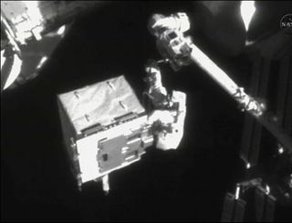 Astronaut Ron Garan rides station robot arm.