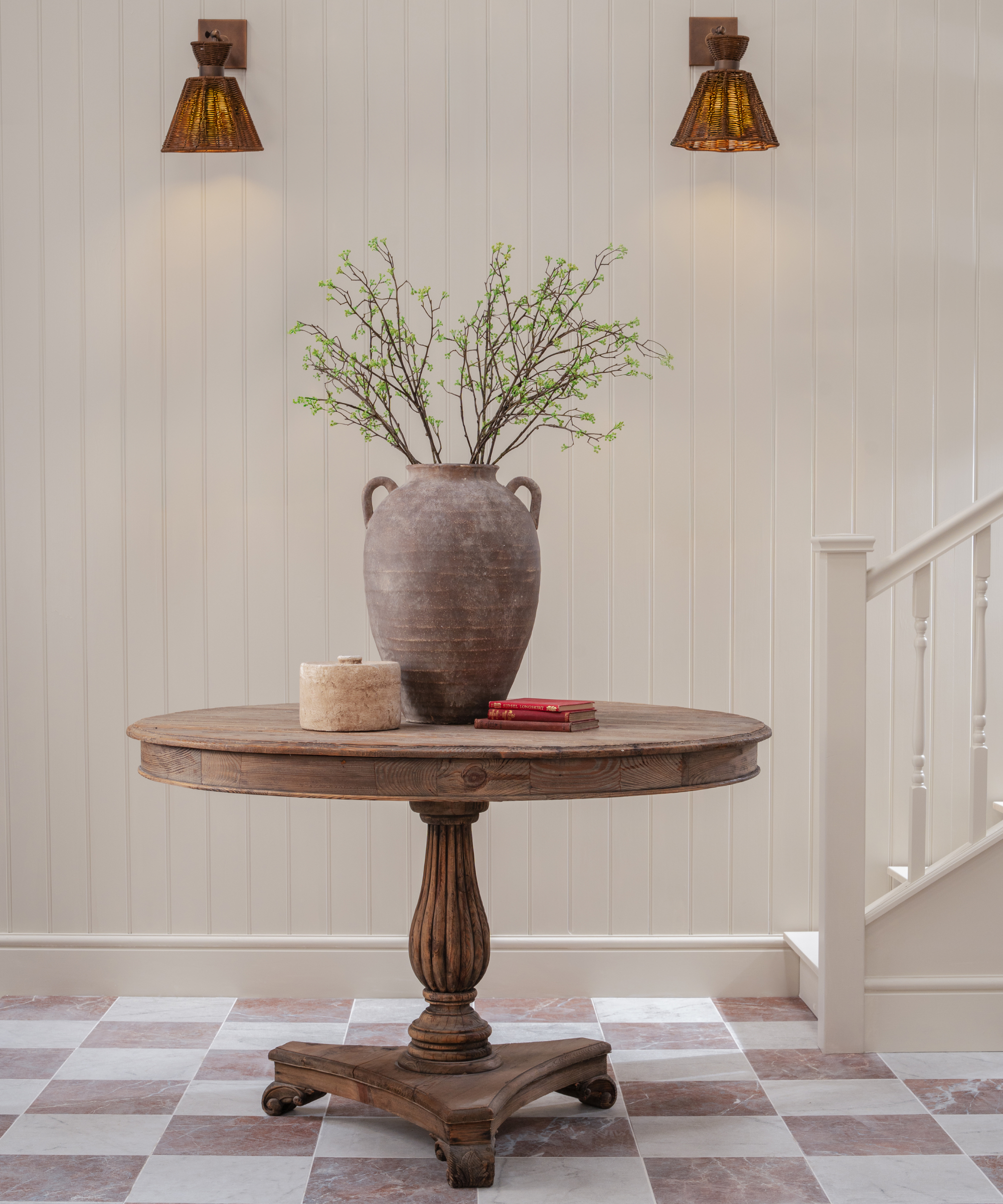 hallway with pink and white tiled floor, wooden table and white staircase, floor to ceiling tongue and grooved wall