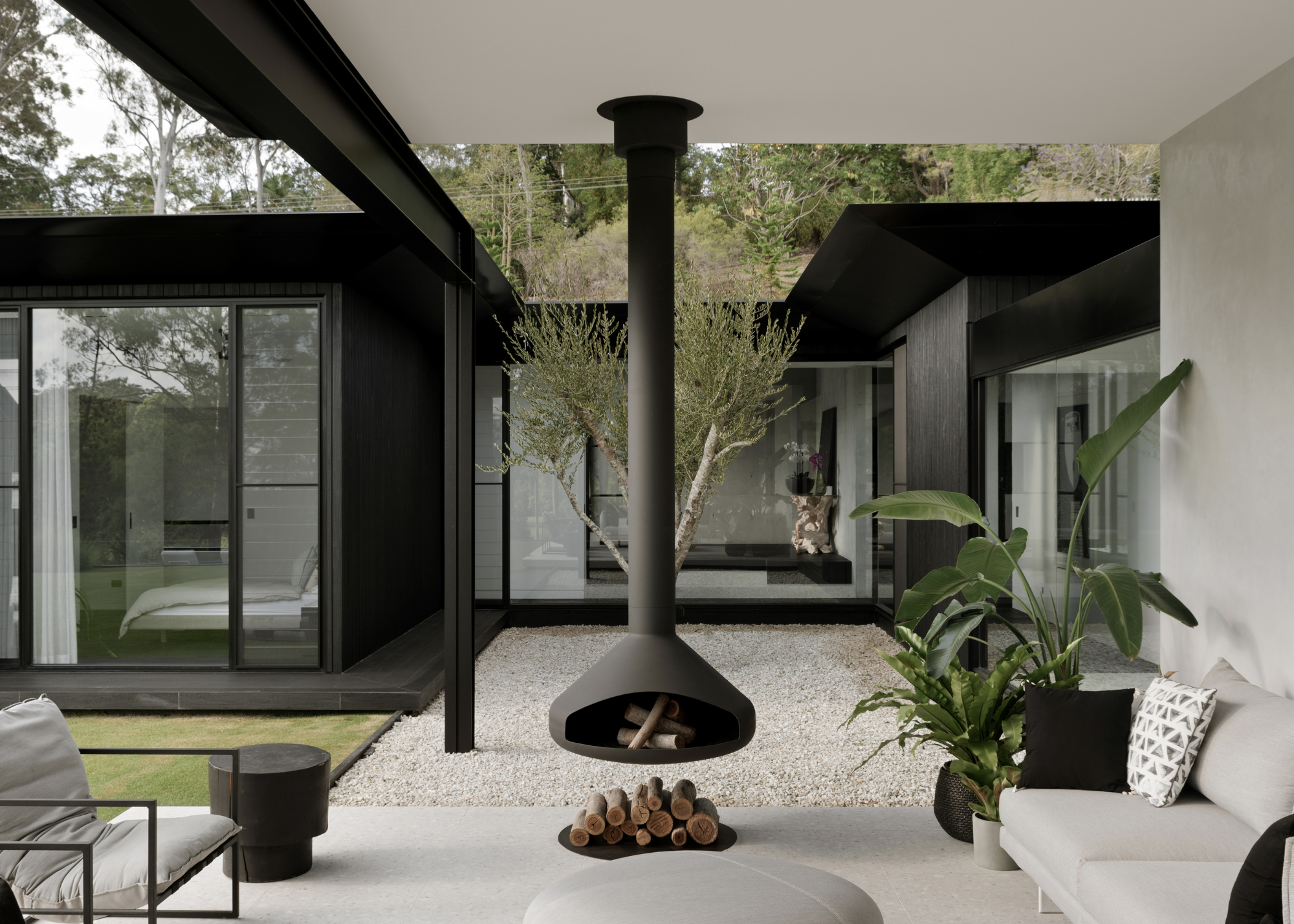 partially covered patio area with a hanging fireplace, black beams and poles, and neutral colored furniture