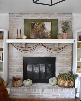 brick fireplace with white wash, vintage artwork, wicker baskets and dried flowers