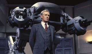 Robocop Dick Jones stands menacingly in front of ED-209