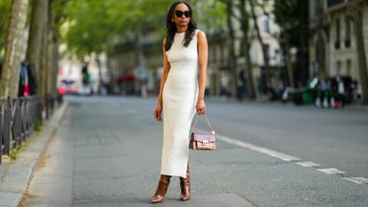 Emilie Joseph wears black sunglasses and a summer dress in Paris