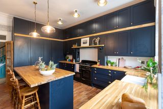 The renovated kitchen worktops have wooden surfaces and blue cabinets fill the kitchen which includes a kitchen island