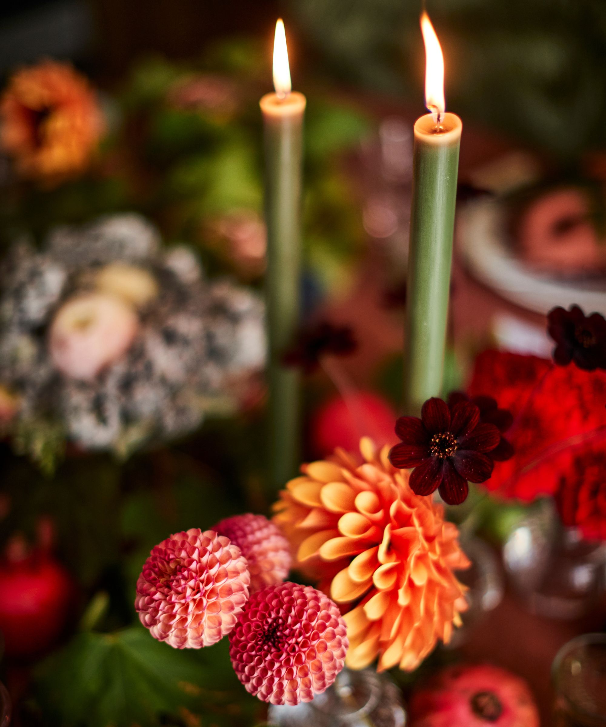 Bright orange and dark red flowers with green taper candles