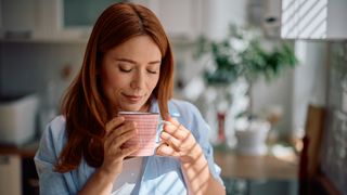 Woman enjoying in smell of fresh coffee in the kitchen.