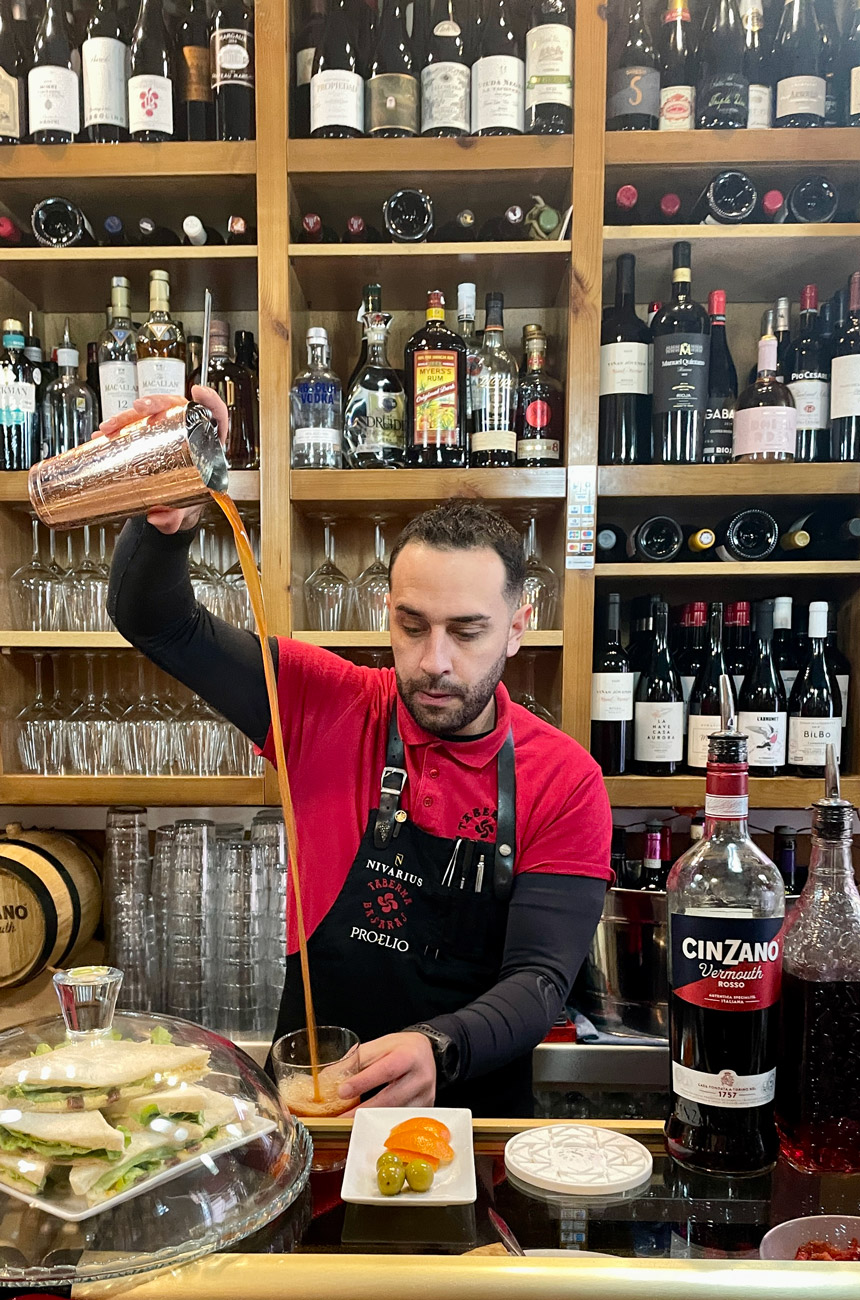 A bartender pouring a cocktail into a glass