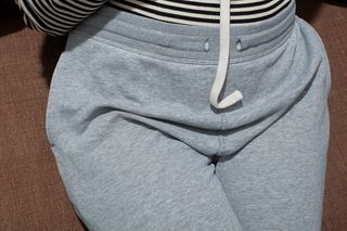 Closeup of a woman's waist. She is wearing grey tracksuit pants.