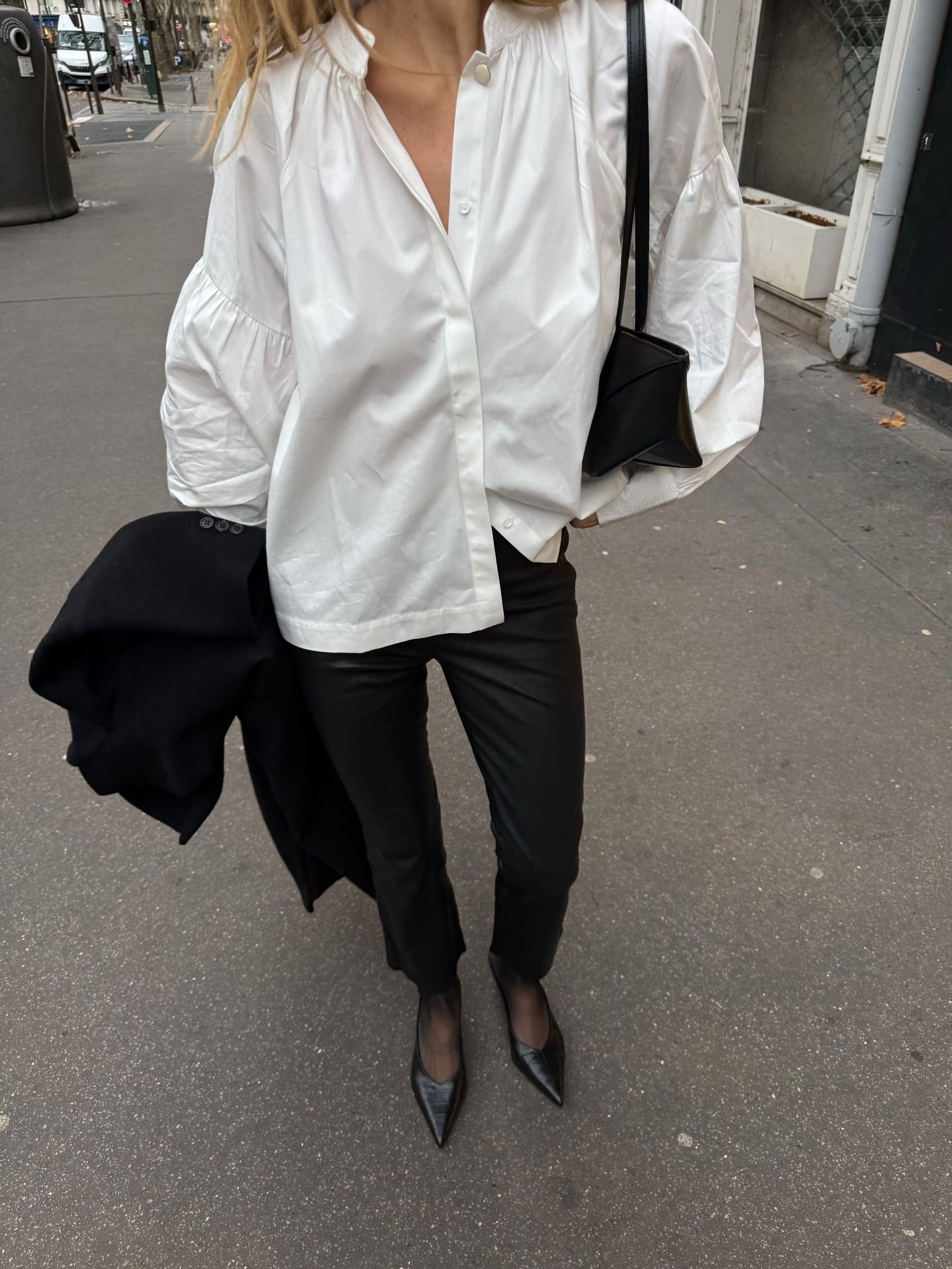 French woman wearing white button-down shirt, black jeans, and black leather shoes in Paris.