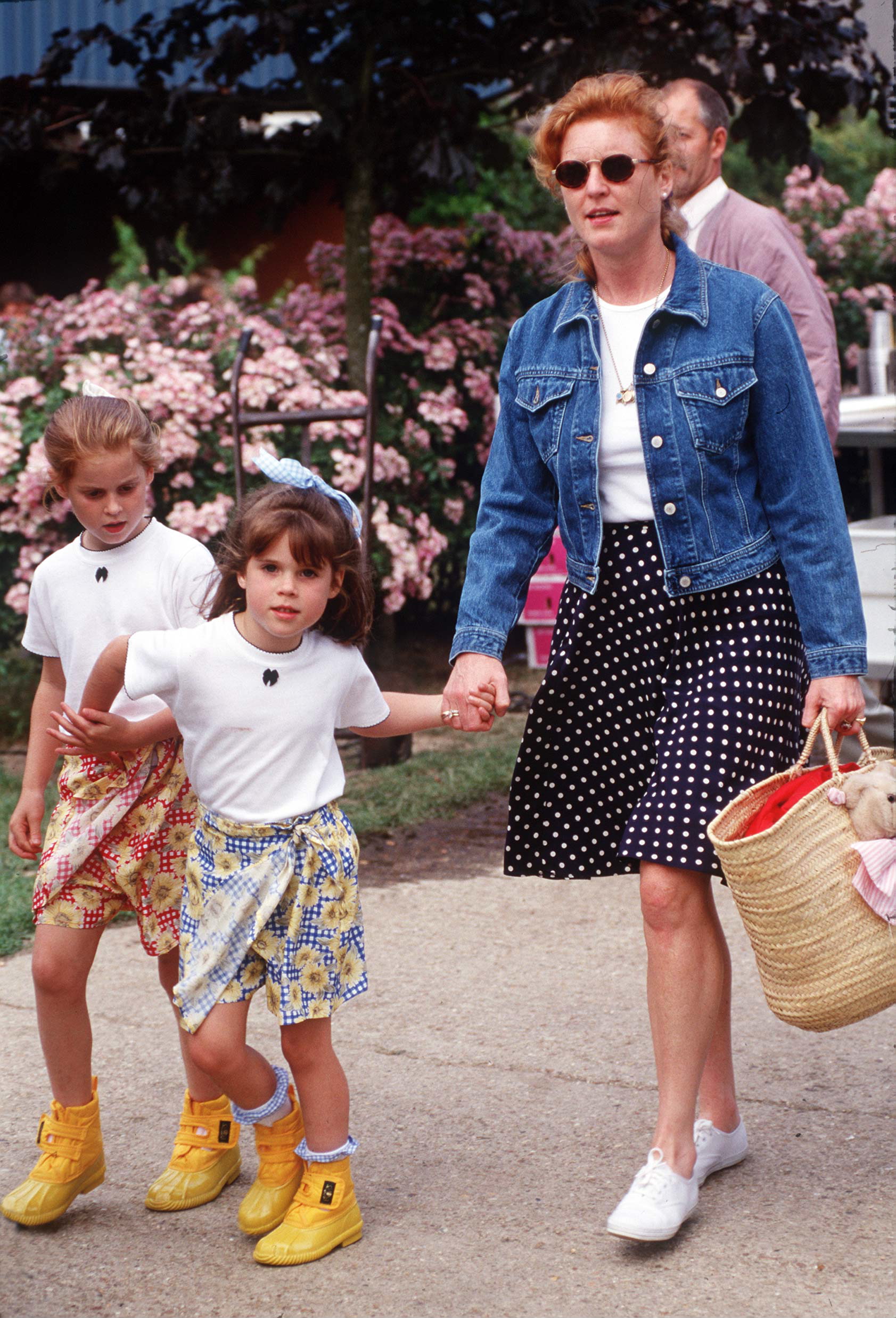 Sarah Ferguson wearing a polka dot skirt holding hands with Princess Eugenie and Princess Beatrice
