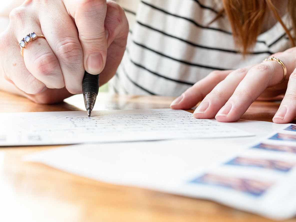 A woman writes a postcard.