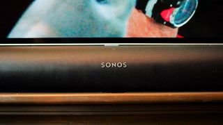 The Sonos Arc lays in front of a TV.