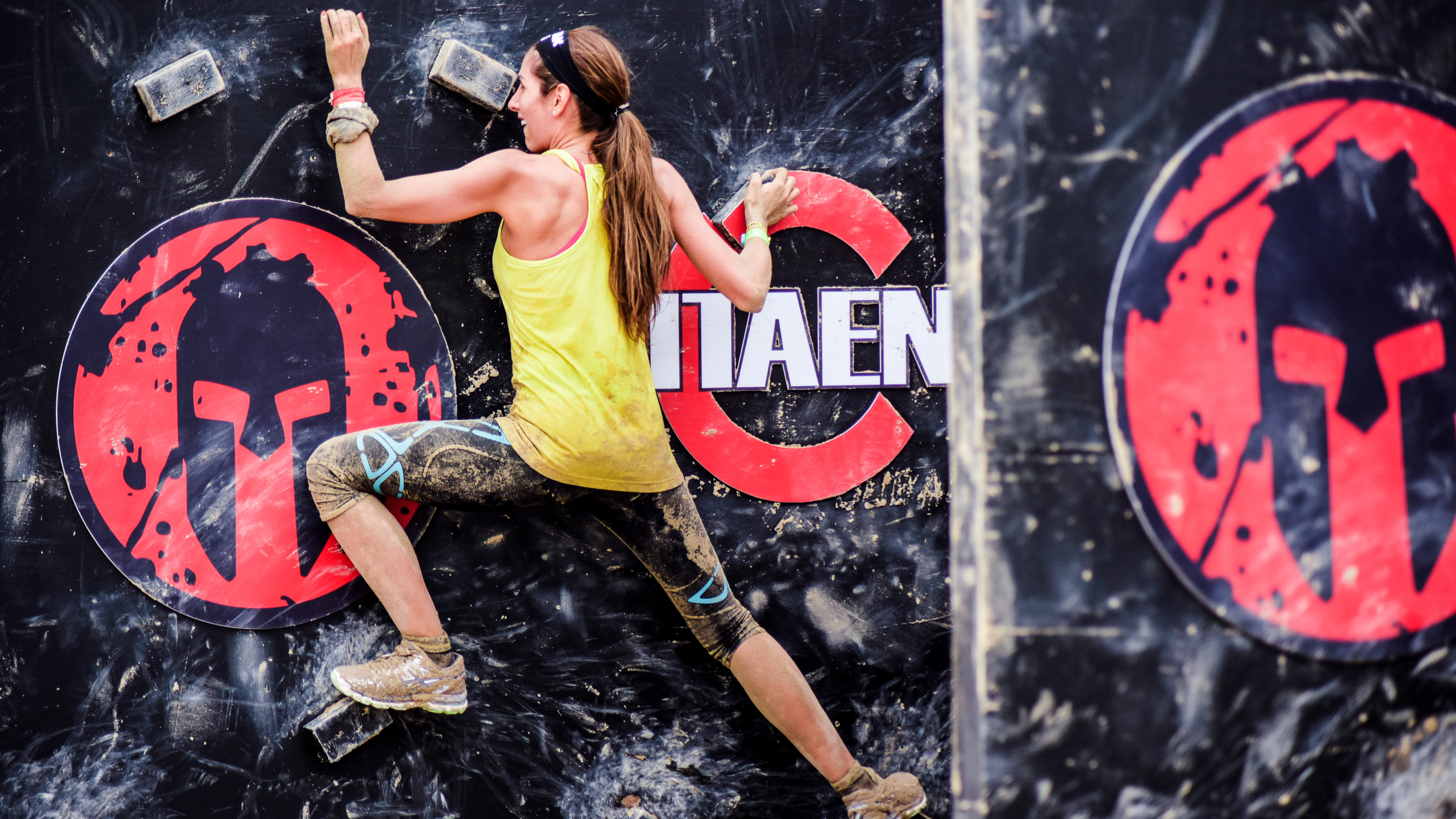 a woman scaling a wall in a Spartan race