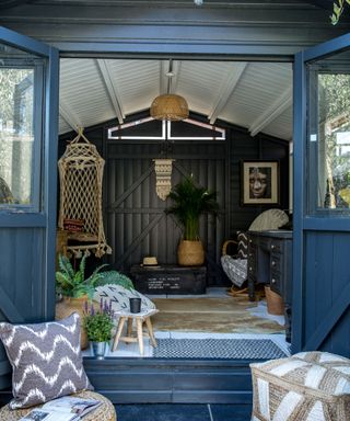 Boho garden room in mono palette with black and white painted floor, ceiling, walls and exterior, hanging chair, woven textures, mixed patterns, and layered textiles.