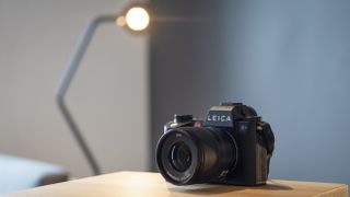 Leica SL3 camera on a wooden surface against a blue background