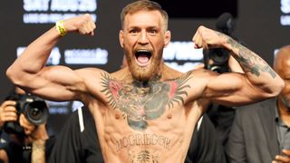 Conor McGregor poses on the scale during an official weigh-in