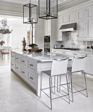 A white kitchen demonstrating marble white kitchen backsplash ideas that are carried through to the countertops and island.
