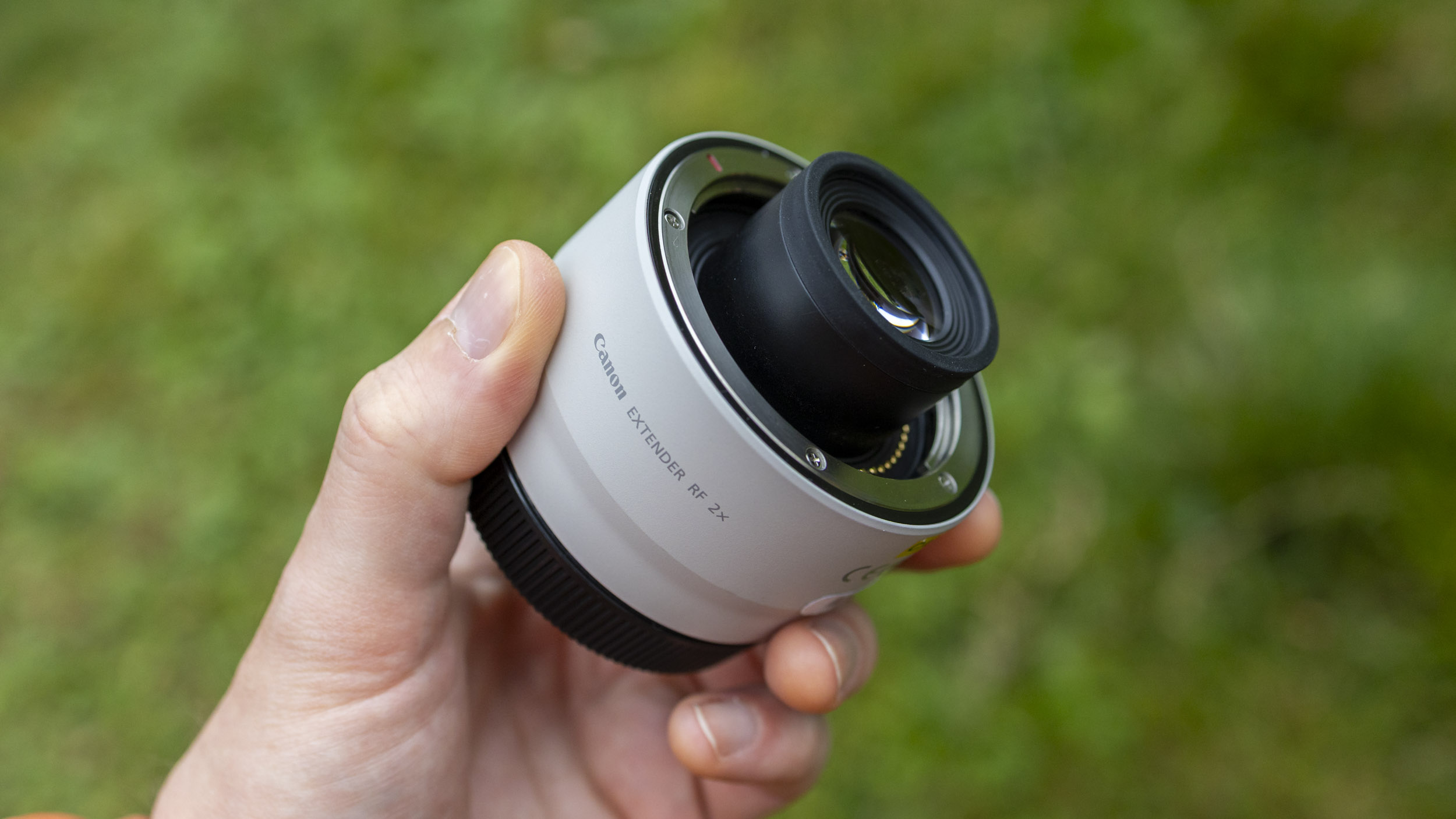 A picture of a photographer holding a white Canon RF 2x Extender