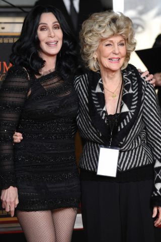 Cher and her mother Georgia Holt standing with their arms around each other both in black outfits