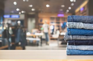 Inside of a clothing store, with a close up of a pile of jeans with different washes