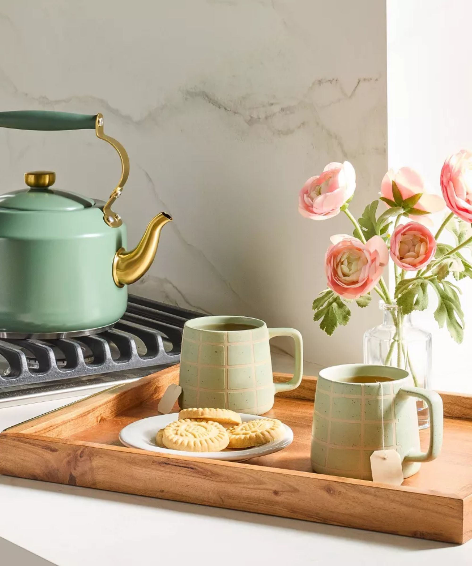 Pastel green mugs on wood tray next to peony vase and mint green tea kettle