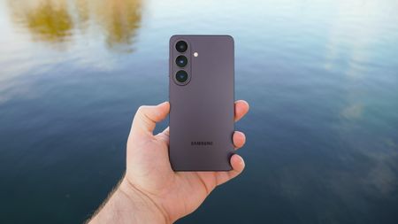 The Samsung Galaxy S26 in Black in the hand in front of a lake.