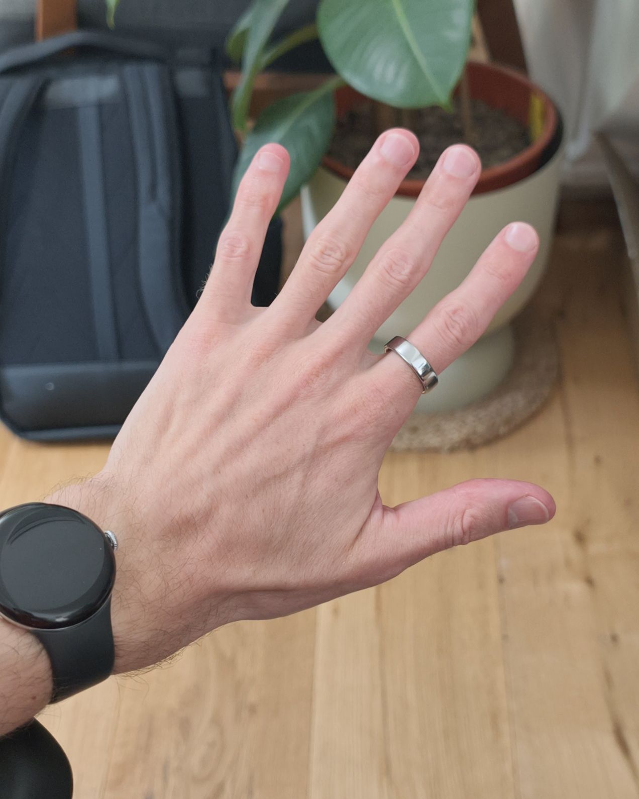 A hand wearing a watch and a silver ring