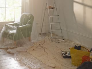 room prepared for painting with step ladder and dust sheets