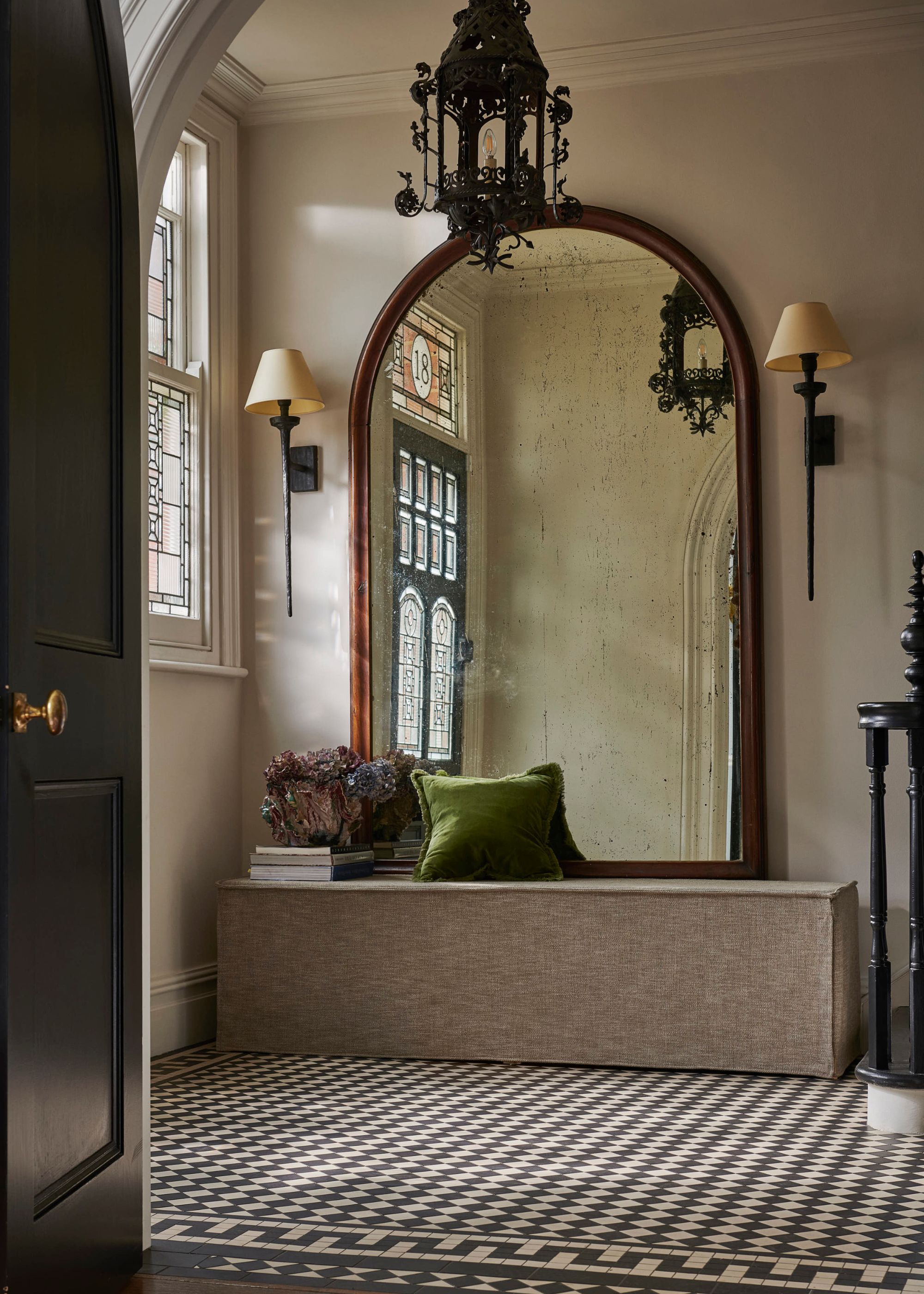 entryway with tiled floor, bench with large curved mirror leaning against it