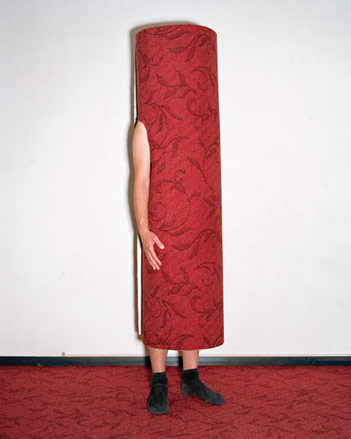 A man wrapped in a red carpet standing on a red carpet.