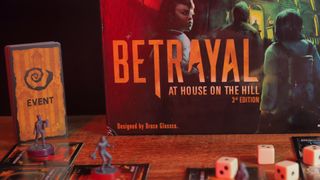 Betrayal at House on the Hill box, cards, and tokens on a wooden table against a black background